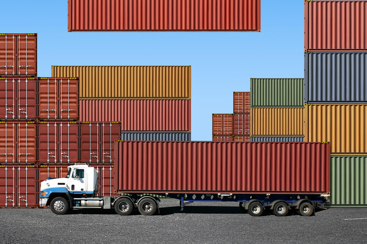 Image of 10 wheel commercial truck with shipping containers in the background